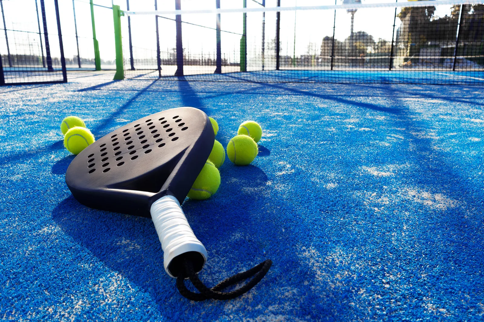 Padel racket and balls on blue monofilament padel turf